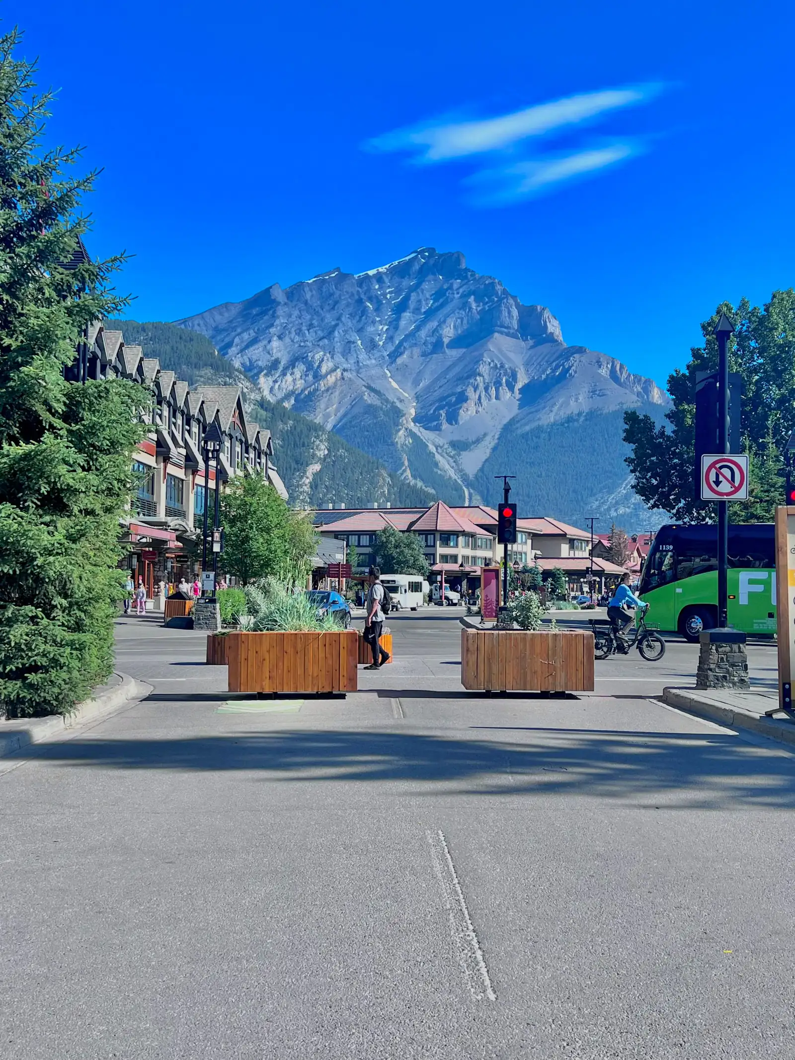 Banff Avenue with planters, cyclists and a mountain rising behind the town