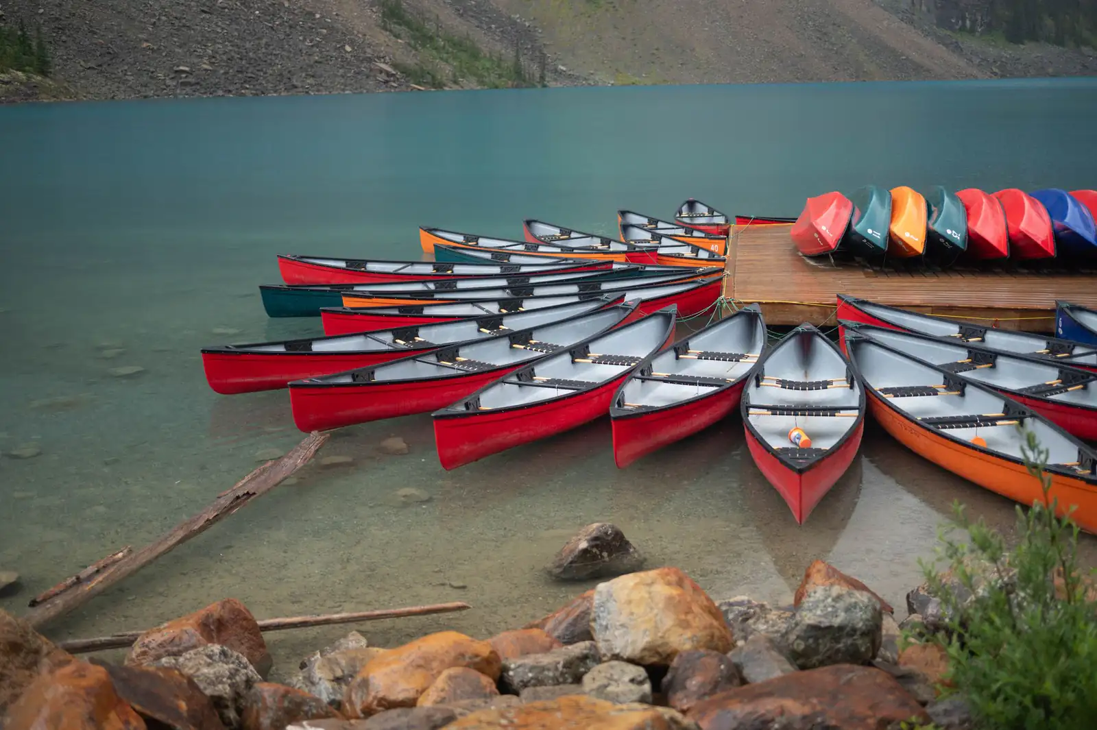 Rows of red canoes lined up at a lakeshore dock
