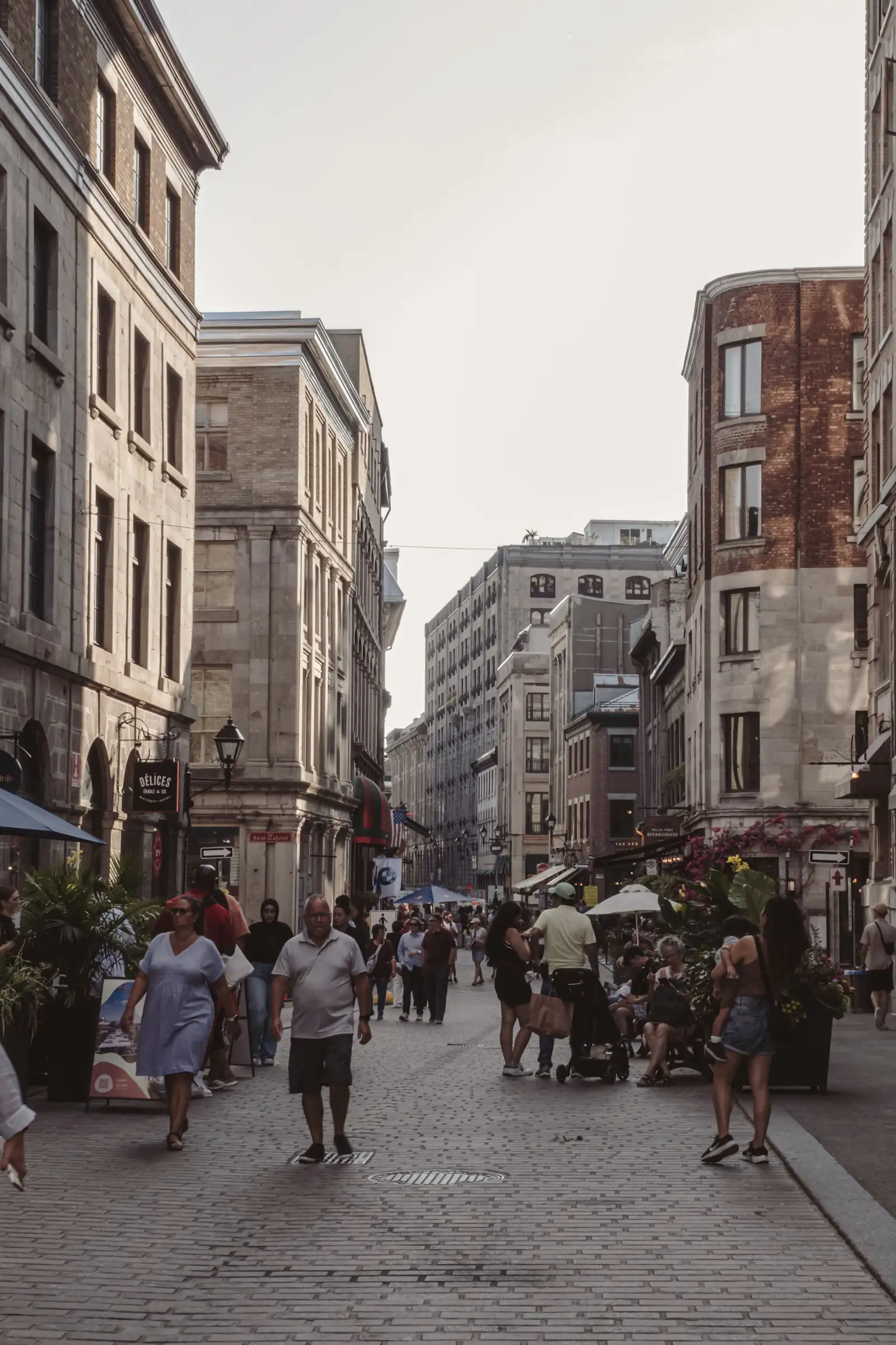 Pedestrians on a lively street lined with historic stone buildings in Old Montreal
