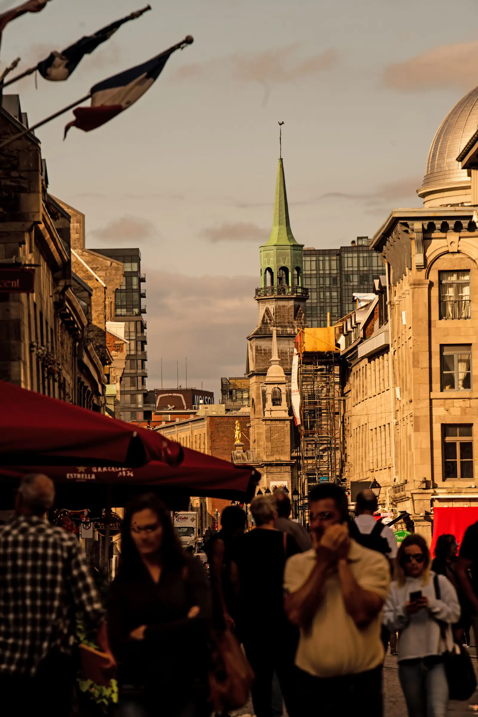 Evening light on historic buildings and a church spire above a busy street in Old Montreal