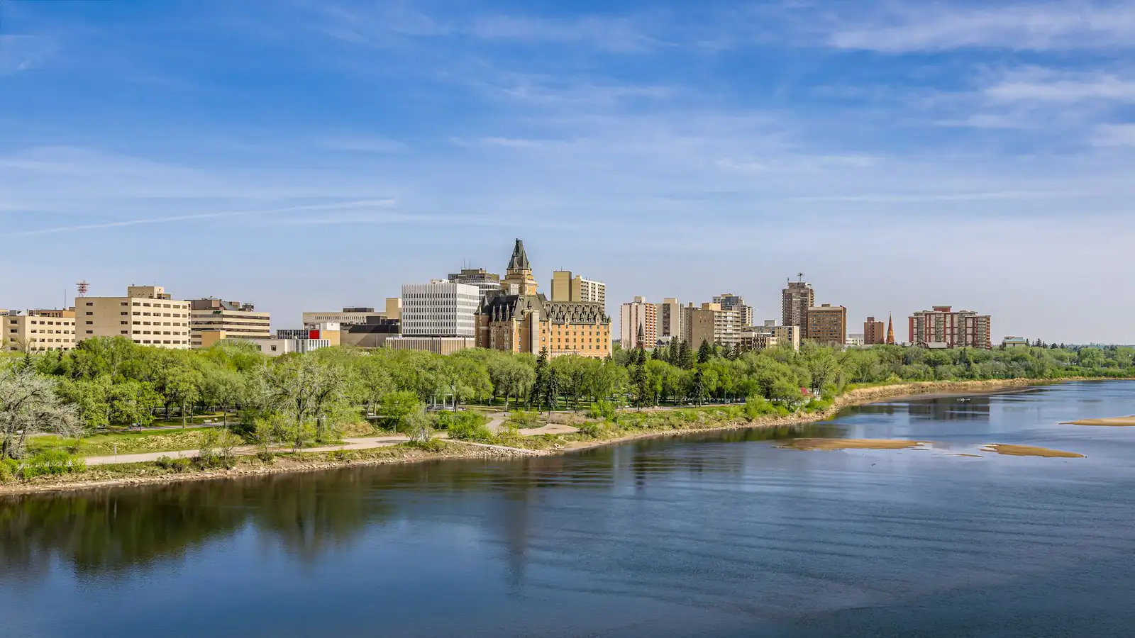 The South Saskatchewan River with green riverbanks and downtown Saskatoon beyond