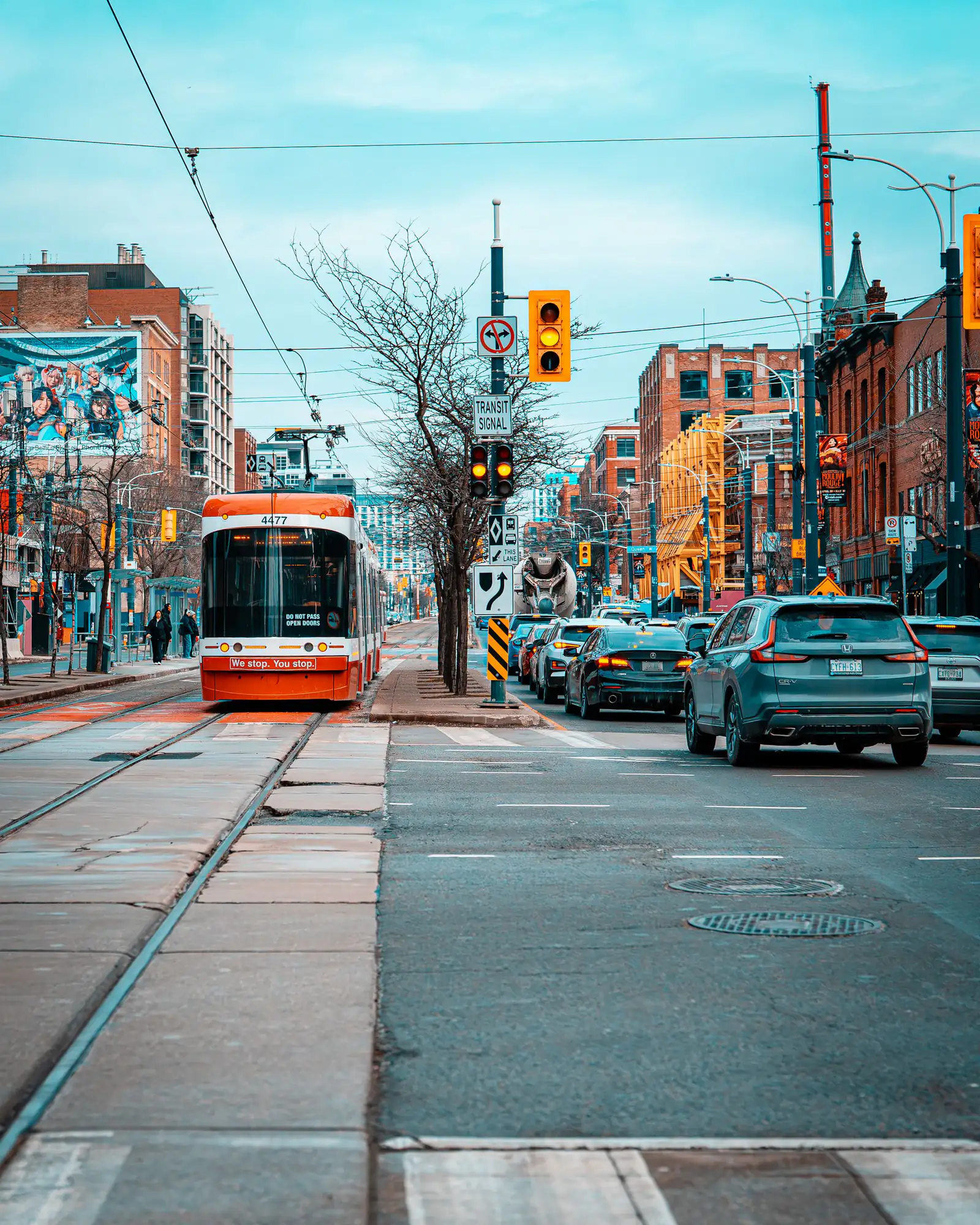 A red Toronto streetcar travelling along a busy downtown street